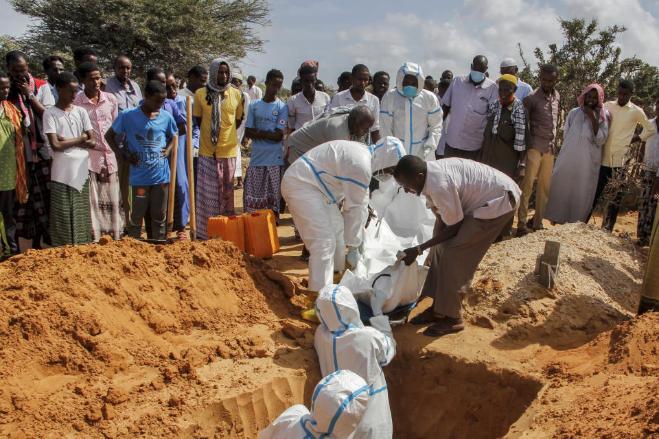 In this photo taken Wednesday, May, 13, 2020, medical workers in protective suits, surrounded by mourners, bury Ibrahim Hassan, 56, in Mogadishu, Somalia. Years of conflict, instability and poverty have left Somalia ill-equipped to handle a health crisis like the coronavirus pandemic. (AP Photo/Farah Abdi Warsameh)