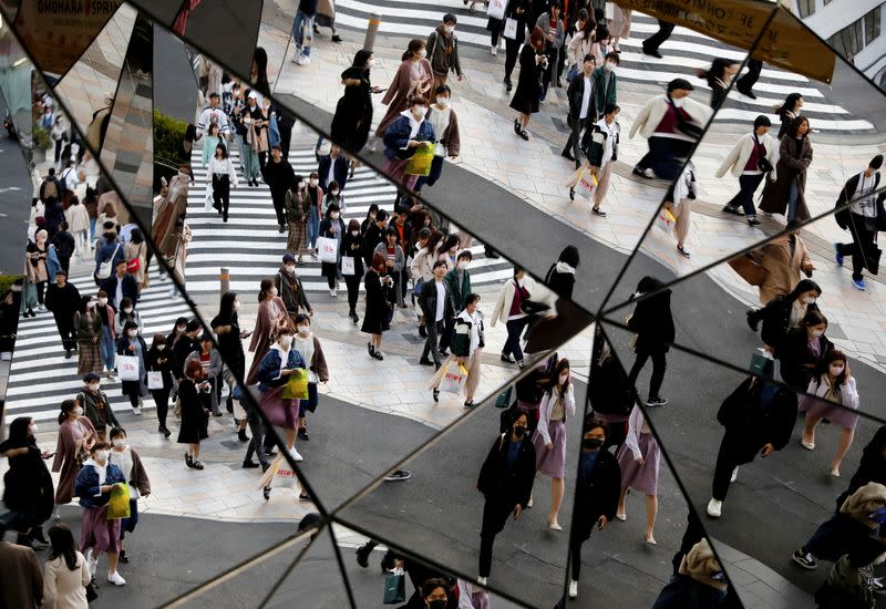 FILE PHOTO: Passersby wearing protective face masks, following an outbreak of the coronavirus disease (COVID-19), are reflected in mirrors at a shopping center in Tokyo