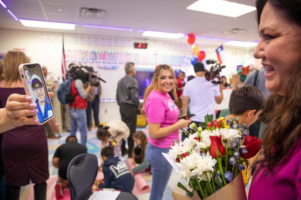 Fourth grade teacher Amalia "Dolores" Barragan FaceTimes with her husband after behing presented with a check at Zachary Kolda Elementary School on Wednesday, Feb. 7, 2024, in Corpus Christi, Texas. Friend and Menger Elementary principal Christina Barrera holds her phone up so they can talk.