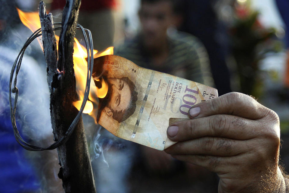 <p>A man burns a 100-bolivar bill during a protest in El Pinal, Venezuela Dec. 16, 2016. (Carlos Eduardo Ramirez/Reuters) </p>