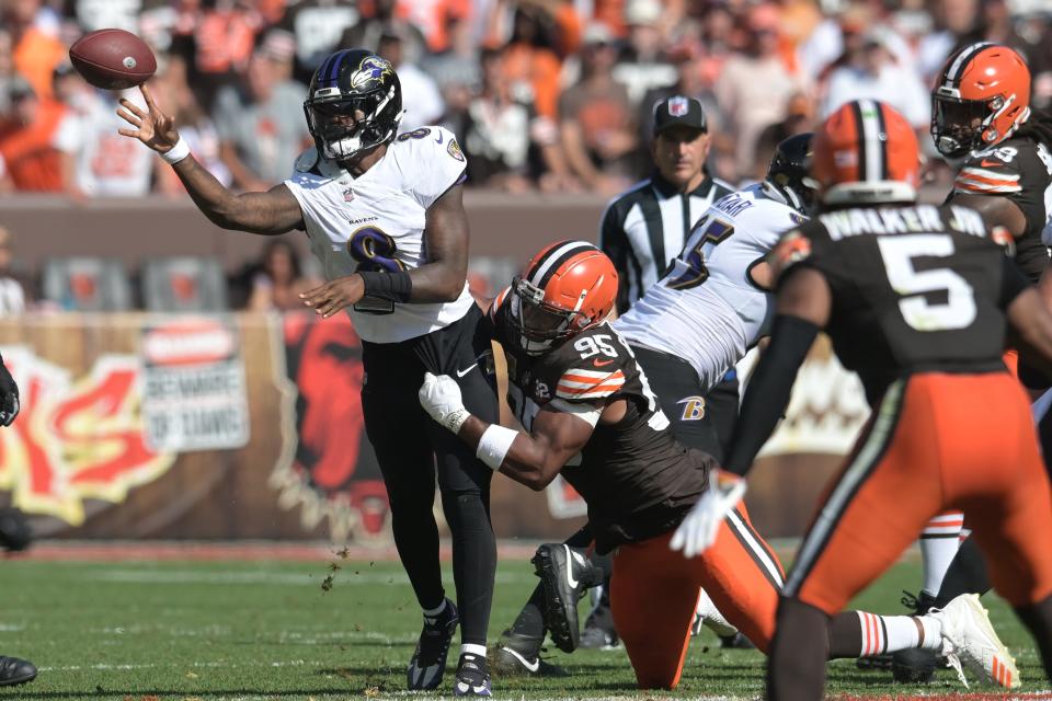 Baltimore Ravens quarterback Lamar Jackson (8) throws a pass as Cleveland Browns defensive end Myles Garrett (95) rushes during the second half at Cleveland Browns Stadium.