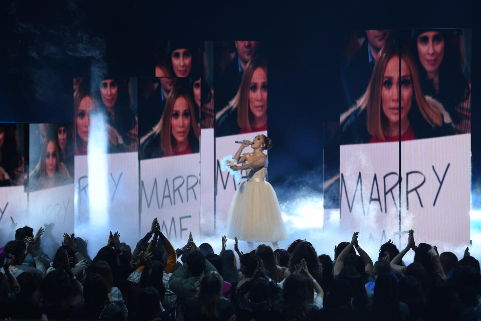 Jlo is performing in front of "Marry me" signs