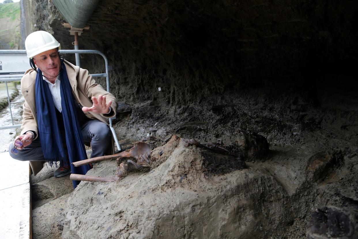 wo archaeologists, with the director of the excavations, Francesco Sirano (first on left), near the skeleton of the last fugitive, the last person who was trying to escape from Herculaneum during the eruption of the volcano Vesuvius, which in 79 AD. destroyed the cities of Herculaneum and Pompeii.