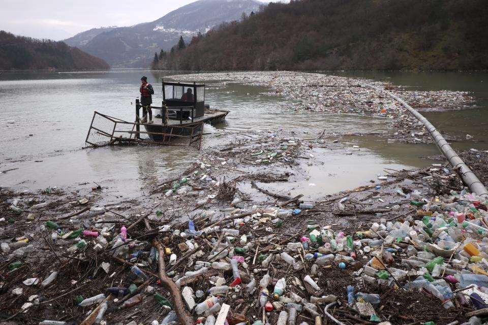 FILE - Utility company workers push the waste to the shore of Lim river near Priboj, Serbia, Jan. 30, 2023. (AP Photo/Armin Durgut, File)