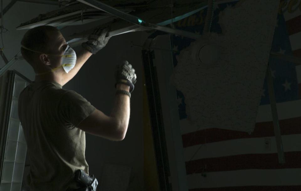 U.S. Air Force Staff Sgt. Matthew Parker, a U.S. Central Command Material Recovery Element technician, tears down broken metal and ceiling tiles the day after a Taliban-led attack on Bagram Airfield, Afghanistan, Dec. 12, 2019.