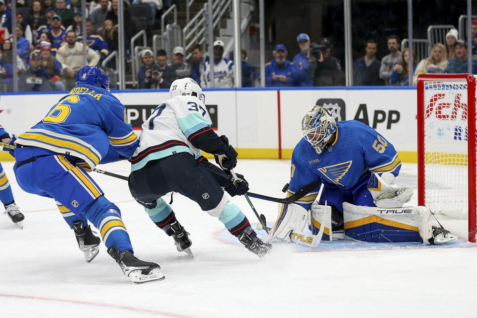 St. Louis Blues goaltender Jordan Binnington (50) deflects a shot on goal from Seattle Kraken's Yanni Gourde (37) during the first period of an NHL hockey game Saturday, Oct. 14, 2023, in St. Louis. (AP Photo/Scott Kane)