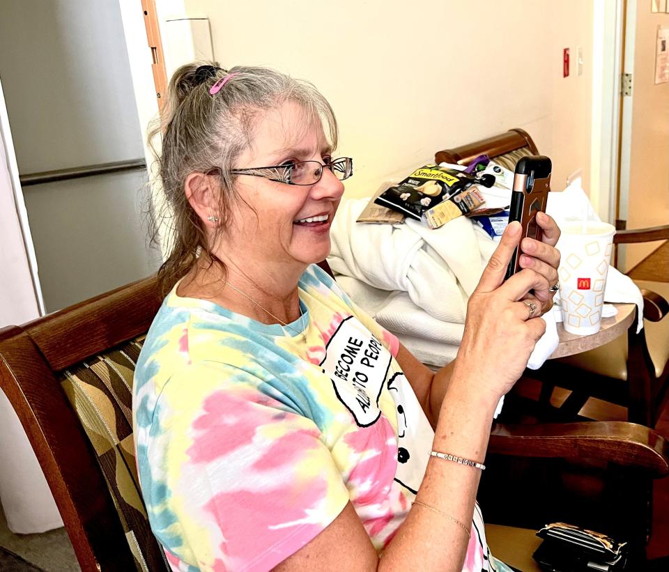 Tamie Moshier, 52, of Goodlettsville, smiles big as she records the Nashville Music Medics serenading her mother, Anita Corwin, Aug. 17, 2022, on her phone at Alive Hospice in Nashville