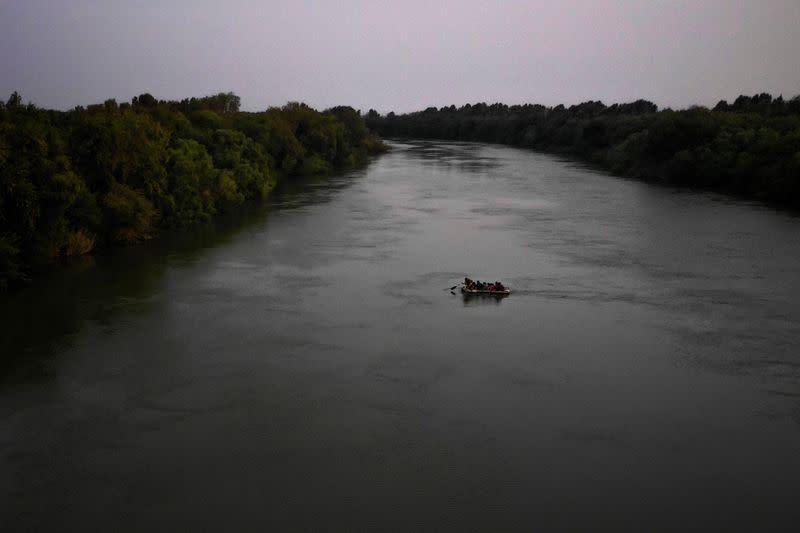 Un hombre en una balsa rema hacia la orilla después de cruzar a Estados Unidos desde México, en Los Ébanos