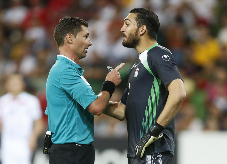 Referee Benjamin Williams of Australia speaks to Iran's goalkeeper Alireza Haghighi following his collision with Bahrain's Faouzi Aaish in the Iranian penalty box during their Asian Cup Group C soccer match at the Rectangular stadium in Melbourne