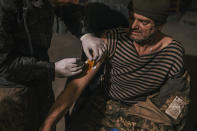 In this photo provided by Azov Special Forces Regiment of the Ukrainian National Guard Press Office, a Ukrainian soldier injured during fighting against Russian forces, gets a medical aid inside the Azovstal steel plant in Mariupol, Ukraine, May 10, 2022. For nearly three months, Azovstal’s garrison clung on, refusing to be winkled out from the tunnels and bunkers under the ruins of the labyrinthine mill. A Ukrainian soldier-photographer documented the events and sent them to the world. Now he is a prisoner of the Russians. His photos are his legacy.(Dmytro Kozatski/Azov Special Forces Regiment of the Ukrainian National Guard Press Office via AP)