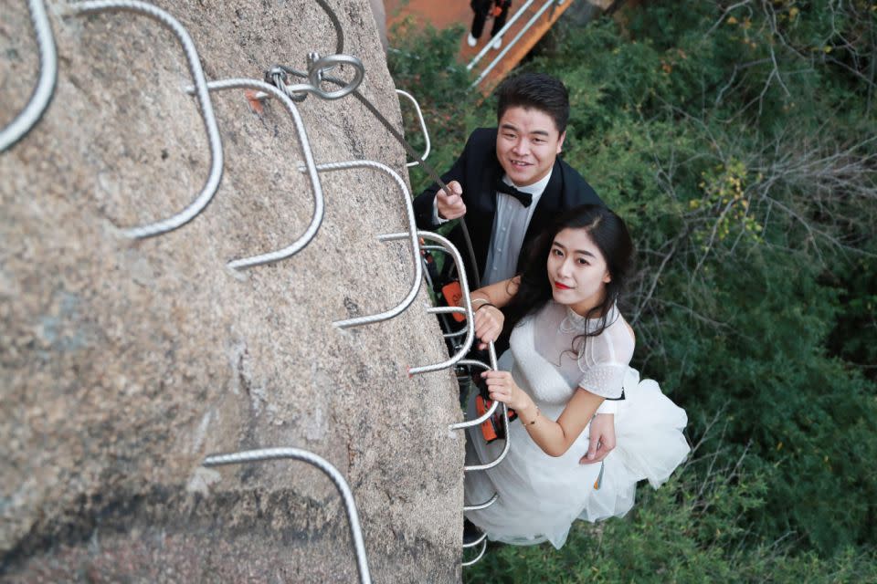 These incredible snaps show the bride and groom clinging to the side of the cliff, dressed-to-impress in their wedding gear. Photo: Australscope