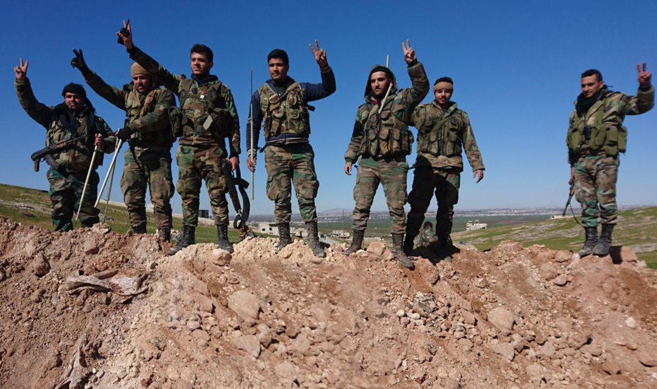 FILE - This Feb. 9, 2020, file photo released by the Syrian official news agency SANA, Syrian army soldiers flash the victory sign in the village of al-Eis, in Aleppo province, Syria. Syria’s civil war has long provided a free-for-all battlefield for proxy fighters. But in its ninth year, the war is drawing major foreign actors into direct conflict, with the threat of all-out confrontations becoming a real possibility. (SANA via AP, File)