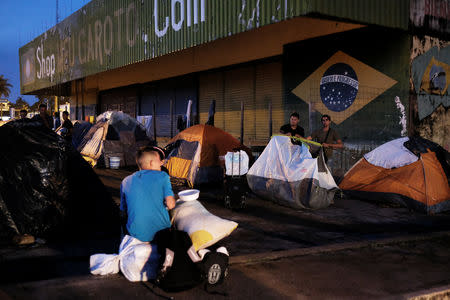 FILE PHOTO: Venezuelan men erect their tent to sleep as they wait to show their passports or identity cards next day at the Pacaraima border control, Roraima state, Brazil August 8, 2018. Picture taken August 8, 2018. REUTERS/Nacho Doce