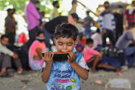 MUMBAI, MAHARASHTRA, INDIA - 2020/05/13: A boy eats a piece of watermelon as they wait to board vehicles during the stranded situation. Due to lockdown situation, most migrants are stuck in Mumbai, some walk and others arrange their own trucks and buses to their home towns, while the police say that the buses are available by the government. (Photo by Ratika More/SOPA Images/LightRocket via Getty Images)