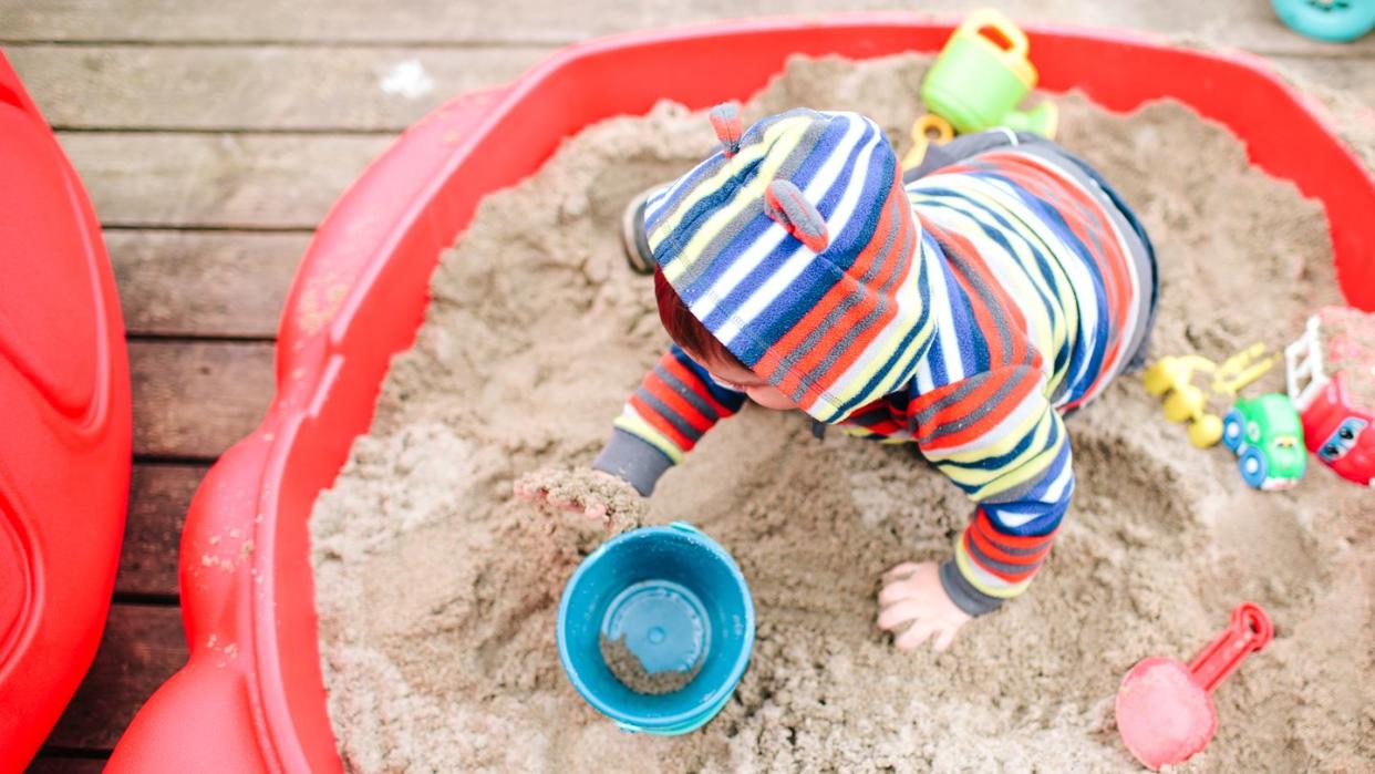 kid playing in sandbox with beach toys