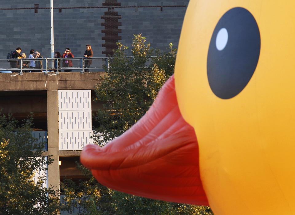 Spectators photograph a giant inflatable rubber duck, created by Dutch artist Florentijn Hofman, as it is towed up the Allegheny River in Pittsburgh