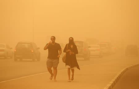 A woman walks with her face covered during a sand storm in Dubai April 2, 2015. REUTERS/Ahmed Jadallah