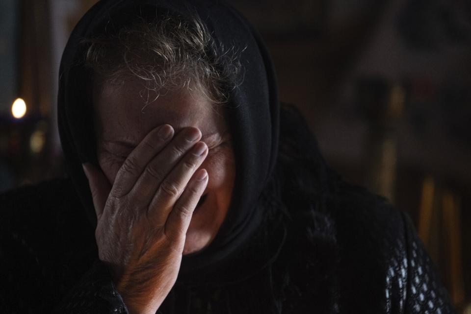 A woman holds her hand over her face as she cries