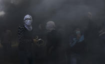 <p>Palestinian protesters hurl stones at Israeli troops while engulfed in smoke from burning tires near the Gaza Strip’s border with Israel, east of Khan Younis, May 14, 2018. (Photo: Adel Hana/AP) </p>