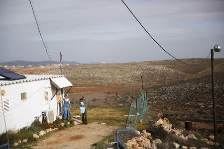 Jewish settler Refael Morris stands with his wife and baby near their house in the unauthorised Jewish settler outpost of Achiya, south of the West Bank city of Nablus January 5, 2016. REUTERS/Ronen Zvulun
