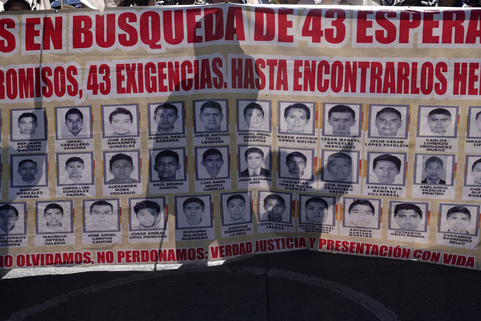 ARCHIVO - Familiares y amigos de los 43 estudiantes de Ayotzinapa desaparecidos marchan con un cartel con las fotos y el nombre de los jóvenes en el noveno aniversario de su desaparición, en Ciudad de México, el 26 de septiembre de 2023. Una corte federal mexicana decidió el jueves 9 de mayo de 2024 que ocho de los militares acusados en el caso Ayotzinapa sigan el proceso en libertad. (AP Foto/Marco Ugarte, Archivo)