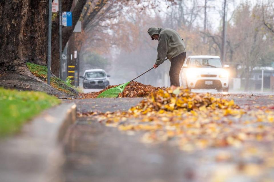 Herbie White keeps the gutter clear of leaves and debris on the 2200 block of 19th Street in Sacramento, as rainfall and and gusty winds from a weather system moving through the region Saturday, Dec. 10, 2022, are felt.