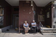 FILE - Pavel Govoryhov, 84, and Tatiana Koneva, 75, residents of Saltivka district, sit on a bench in front of their apartment house in Kharkiv, Ukraine, July 5, 2022. As Russia's invasion of Ukraine grinds into its fifth month, some residents close to the front lines remain in shattered and nearly abandoned neighborhoods. One such place is Kharkiv's neighborhood of Saltivka, once home to about half a million people. Only perhaps dozens live there now, in apartment blocks with no running water and little electricity. (AP Photo/Evgeniy Maloletka, File)