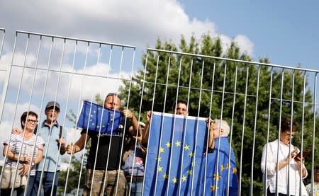 People hold EU flags as they wait for German Chancellor Angela Merkel and Britain's Prime Minister Boris Johnson at the Chancellery in Berlin