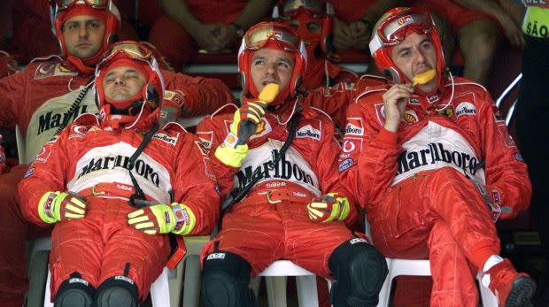 As a Ferrari pit crewman takes a nap, two colleagues enjoy ice cream mid way through the Brazilian Grand Prix
