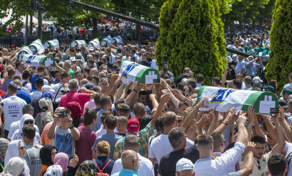 Coffins are being carried for the funeral in Potocari near Srebrenica, Bosnia, Thursday, July 11, 2019. Thousands of mourners, including relatives of the victims, are gathering for a commemoration on the 24th anniversary of the Srebrenica massacre, the worst mass killing in Europe since World War II. The ceremony at a memorial site near Srebrenica included the burial of 33 newly identified victims of the July 11-22, 1995 massacre in which more than 8,000 Bosnian Muslim men and boys were killed in and around the U.N.-protected enclave by Bosnian Serb troops during the Bosnian civil war. (AP Photo/Darko Bandic)