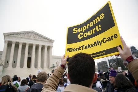 A demonstrator in favor of the Affordable Care Act walks with a sign in front of the Supreme Court in Washington March 4, 2015. REUTERS/Gary Cameron