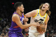 Utah Jazz forward Kelly Olynyk (41) gets fouled by Phoenix Suns guard Devin Booker during the first half of an NBA basketball game, Saturday, Nov. 26, 2022, in Phoenix. (AP Photo/Rick Scuteri)