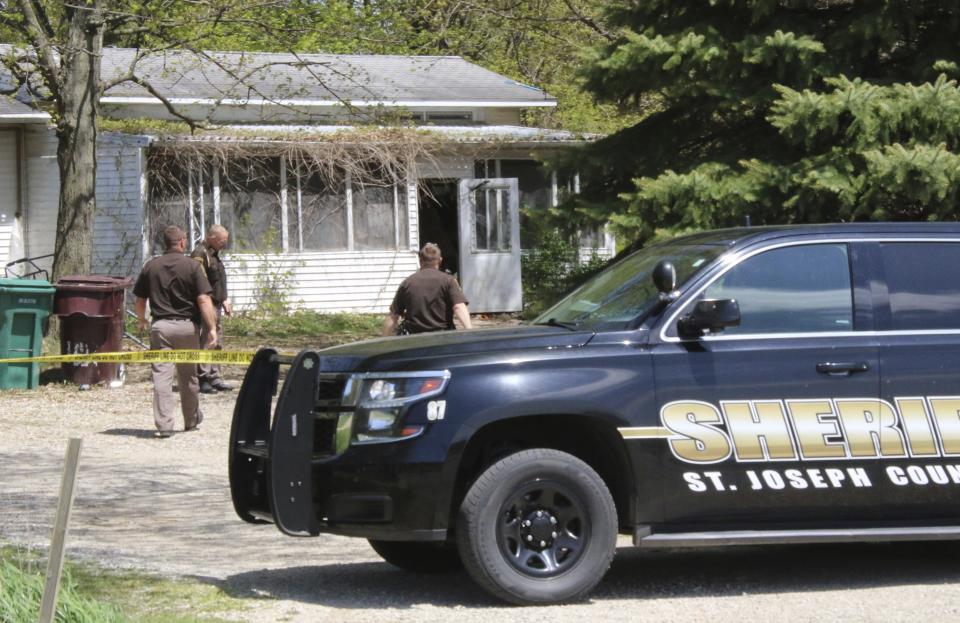 In this Monday, May 6, 2019 photo, St. Joseph County Sheriff deputies stand outside the site where a woman was fatally shot in Fawn River Township, Mich. Authorities say a 9-year-old is suspected in the shooting of a woman in her southern Michigan home. (Corky Emrick/Sturgis Journal via AP)