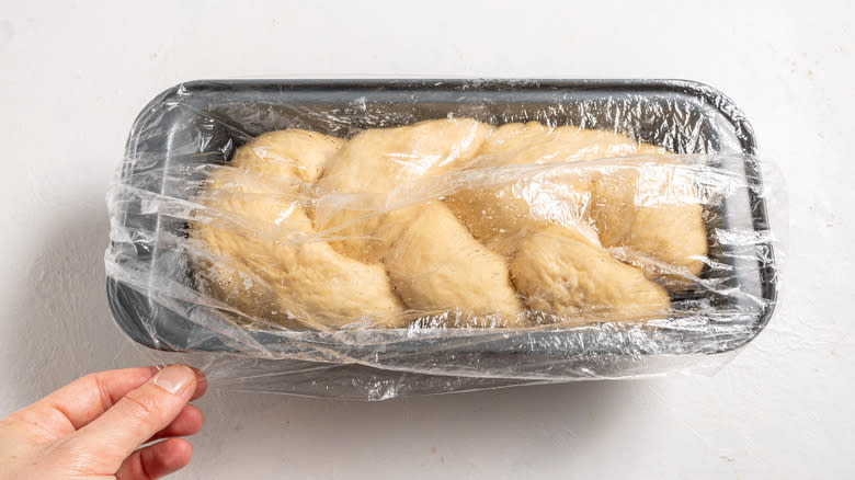 Covering a braided dough in a baking dish with plastic wrap