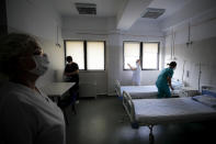 Medical staff check an empty ward, reserved for possible COVID-19 patients, at the Colentina Hospital in Bucharest, Romania, Thursday, Feb. 25, 2021. A year ago, Romania reported its first case of COVID-19, prompting the country's strapped medical system to turn its focus to treating COVID-19 patients. As a result, many patients with other conditions — including HIV but also cancer and other illnesses — have either been denied critical care or stopped going to their regular appointments, fearful of becoming infected.(AP Photo/Vadim Ghirda)