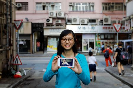 Candy Lau, who was born five months before the Hong Kong's handover to Chinese rule in 1997, poses with her childhood photo in front of the building which she being photographed in 1997, in Hong Kong, China June 6, 2017. REUTERS/Tyrone Siu