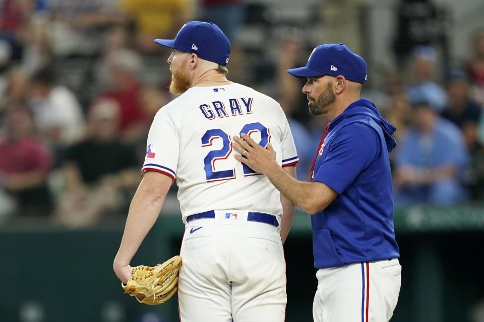 Texas Rangers starting pitcher Jon Gray (22) looks to the outfield after turning the ball over to manager Chris Woodward, right, in the sixth inning of a baseball game against the Philadelphia Phillies, Wednesday, June 22, 2022, in Arlington, Texas. (AP Photo/Tony Gutierrez)