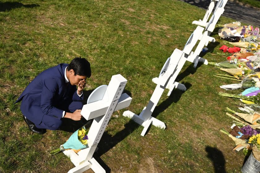 Alexander Reddy, 17, kneels and prays at a cross after leaving flowers at an entry to Covenant School, Tuesday, March 28, 2023, in Nashville, Tenn., which has become a memorial for the victims of Monday's school shooting. (AP Photo/John Amis)