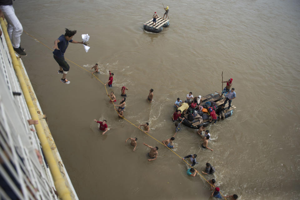Migrants tired of waiting to cross into Mexico, jumped from a border bridge into the Suchiate River, in Tecun Uman, Guatemala, on Friday, Oct. 19, 2018. Some of the migrants traveling in a mass caravan towards the U.S.-Mexico border organized a rope brigade to ford its muddy waters. (AP Photo/Oliver de Ros)