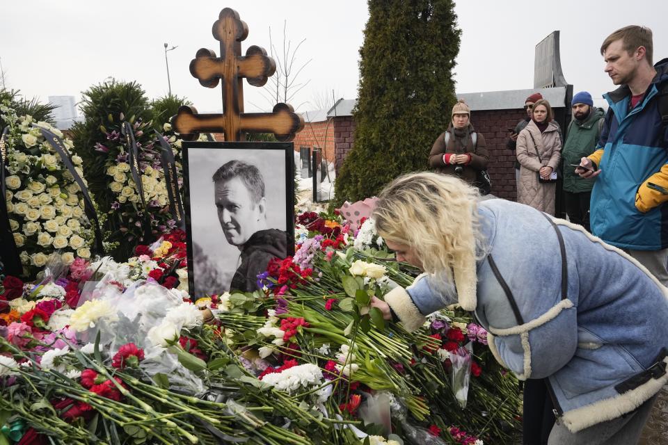 A woman lays flowers at the grave of Alexei Navalny a day after his funeral at the Borisovskoye Cemetery, in Moscow, Russia, on Saturday, March 2, 2024. Navalny, who was President Vladimir Putin's fiercest foe, was buried after a funeral that drew thousands of mourners amid a heavy police presence. (AP Photo)