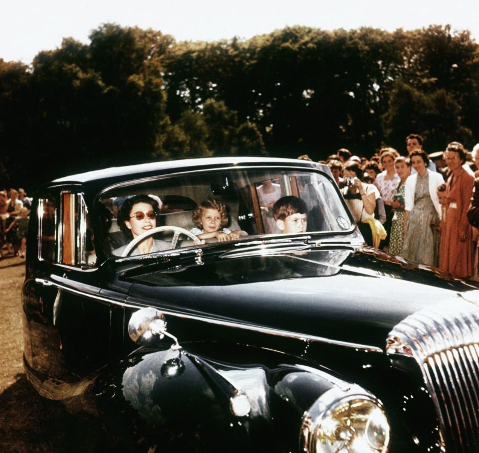 <p>In one of her first driving photos, the Queen chauffeured her two young children, Prince Charles and Princess Anne, as onlookers gathered around them. </p>