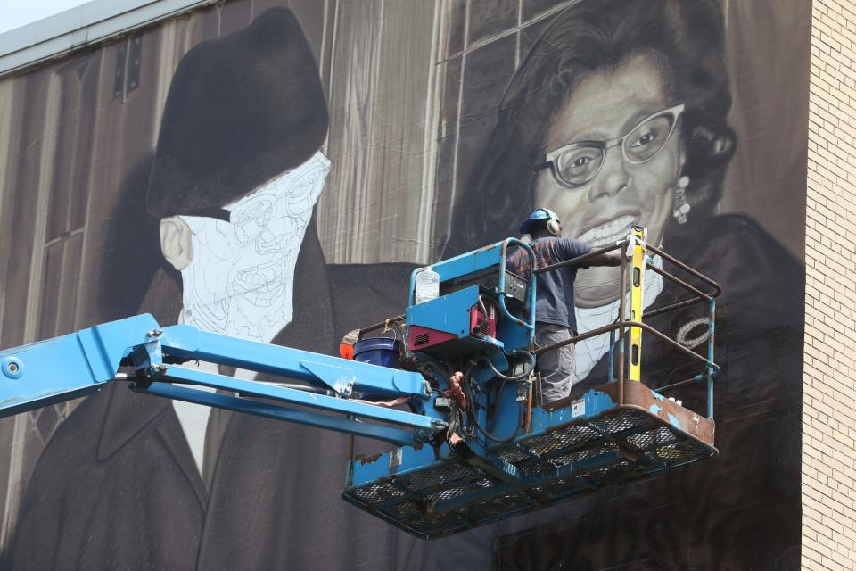 Ephraim Gebre works on painting Connie Mitchell's neck.