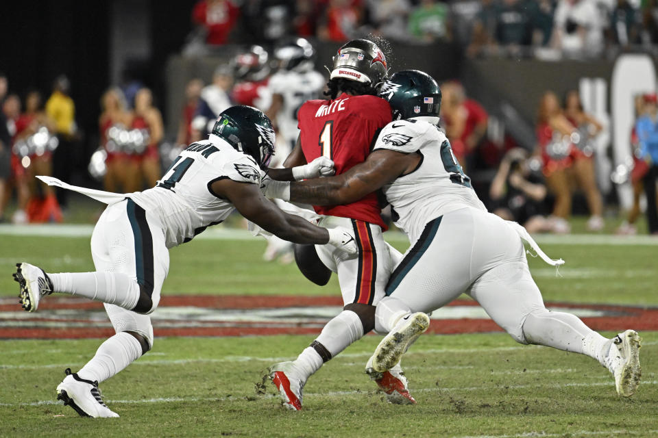 Jalen Carter (98) y Sydney Brown (21) de los Philadelphia Eagles tacklean a Rachaad White (1) de los Tampa Bay Buccaneers para forzar un fumble durante el juego de lunes por la noche, en Tampa, Florida. Lunes 25 de septiembre de 2023. (AP Foto/Jason Behnken)