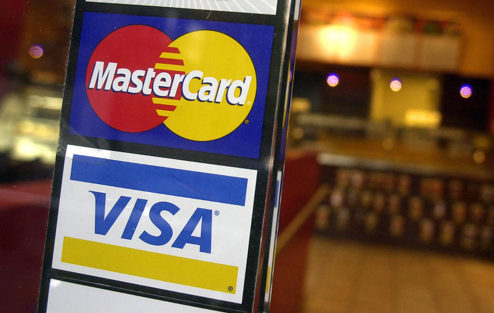 FILE - This April 22, 2005, file photo, shows logos for MasterCard and Visa credit cards at the entrance of a New York coffee shop. Visa and Mastercard are dropping out of Facebook’s Libra project, a potentially fatal blow to the social network’s plan for a worldwide digital currency, Friday, Oct. 11, 2019. (AP Photo/Mark Lennihan, File)