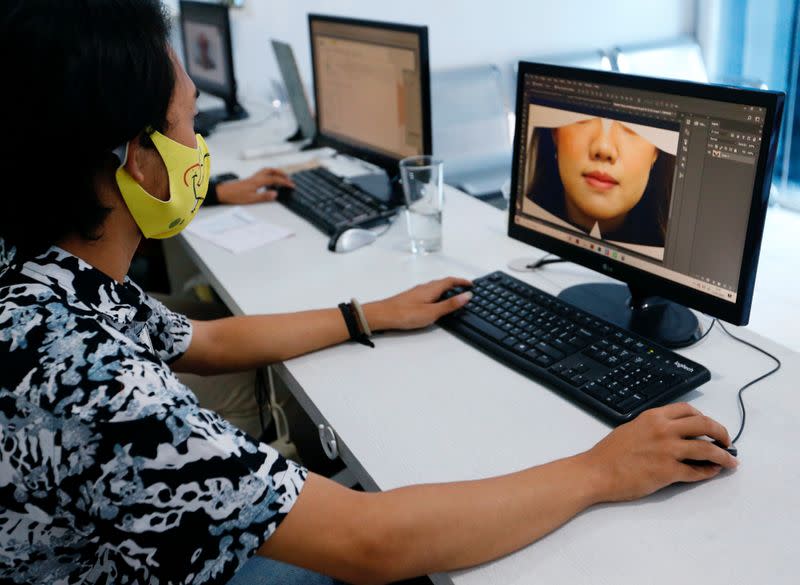 A printing shop employee editing customer's photo designs a face mask, amid the coronavirus disease (COVID-19) outbreak, in Jakarta