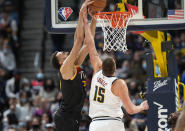 Utah Jazz center Rudy Gobert, left, dunks as Denver Nuggets center Nikola Jokic defends in the first half of an NBA basketball game Sunday, Jan. 16, 2022, in Denver. (AP Photo/David Zalubowski)