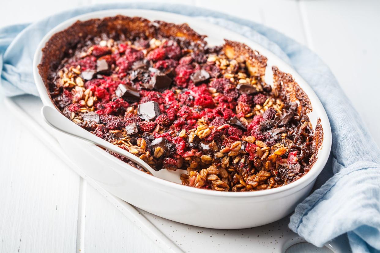 Baked oatmeal with berries and chocolate in a white dish. Plant bsed diet concept.