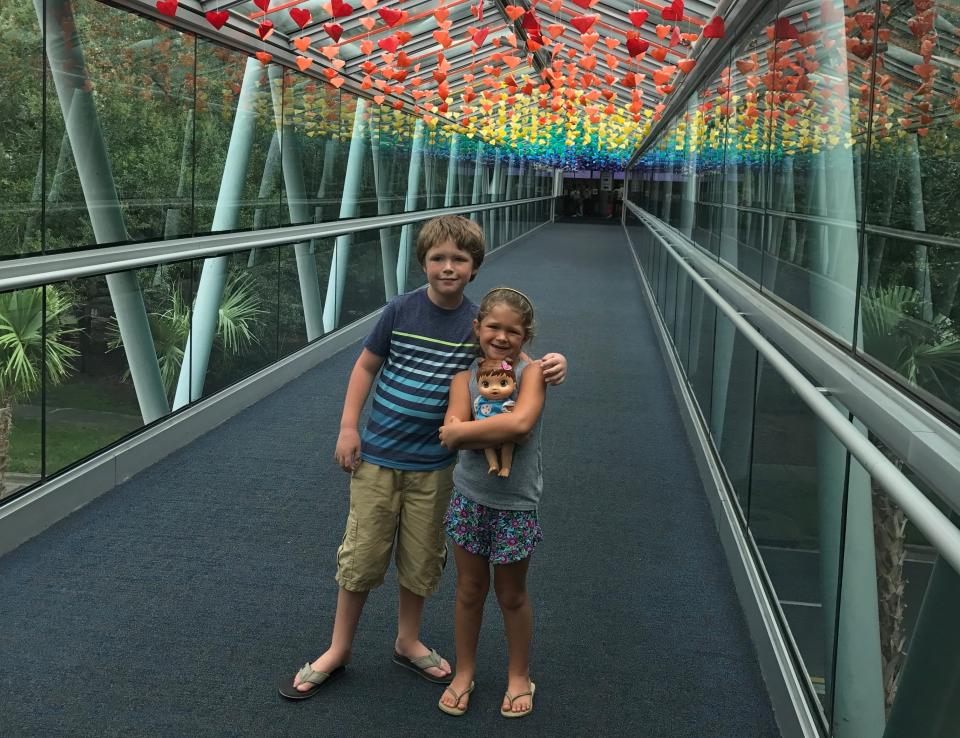 two kids on a walkway underneath a rainbow ceiling