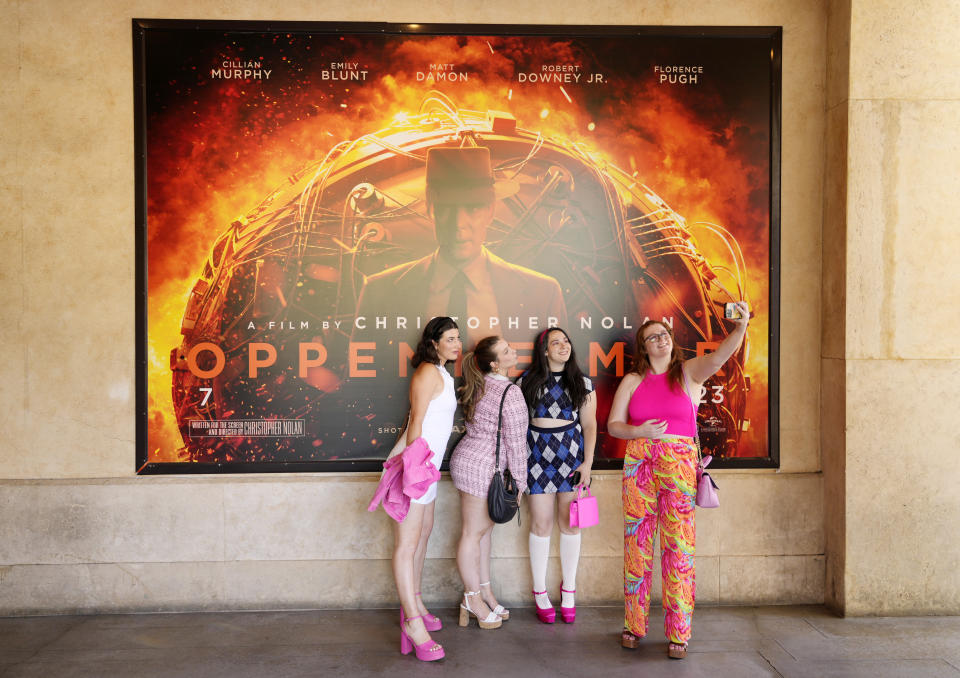 Gabrielle Roitman, de izquierda a derecha, Kayla Seffing, Maddy Hiller y Casey Myer se toman una selfie frente a un cartel de la película "Oppenheimer" antes de asistir a una proyección anticipada de "Barbie", el jueves 20 de julio de 2023 en los cines AMC The Grove 14 en Los Ángeles. (Foto AP/Chris Pizzello)