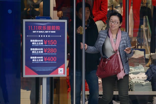 A woman walks out a shop past a 'Singles Day' sales promotional board in Beijing on November 11, 2015. 